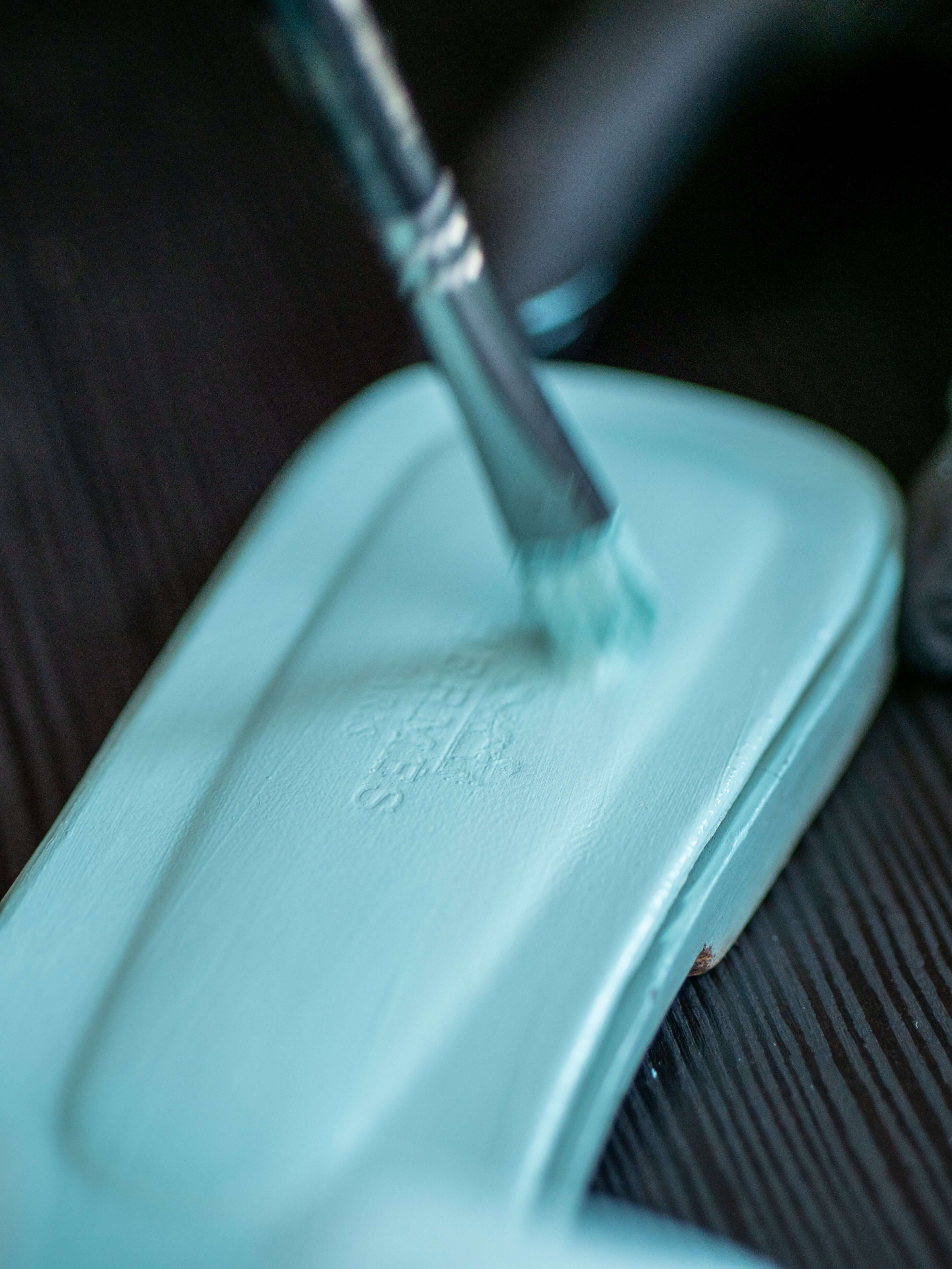 Artisan hand-dyeing a red Hermès Oran sandal using a precision brush during professional leather color restoration service
