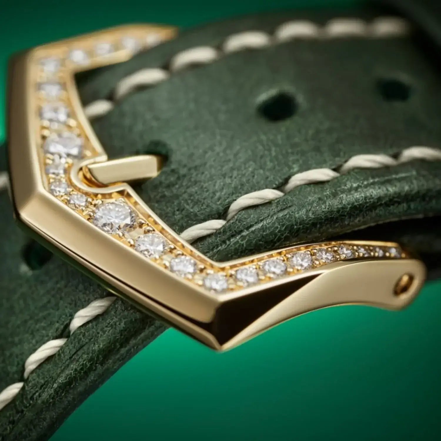 Gold watch buckle with diamonds on a green leather strap
